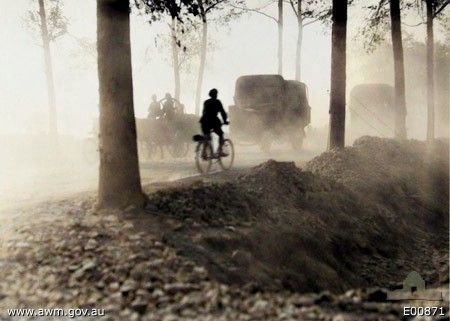the 2nd Australian Divisional Ammunition Column moving up to the front by the dusty Poperinghe road on the way to Ypres during the Third Battle of Ypres, when this road was enveloped day and night in thick grey clouds of dust, raised by the great stream of troops and traffic  which never ceased for weeks on end. Note the man on the bicycle in the foreground.